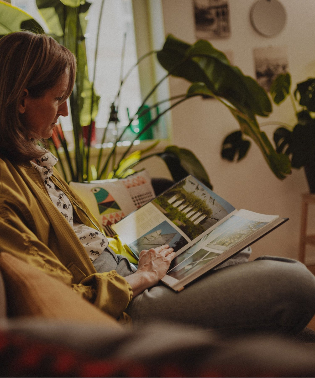 Eine Frau sitzt auf einem Sofa und schaut i ein Fotobuch.